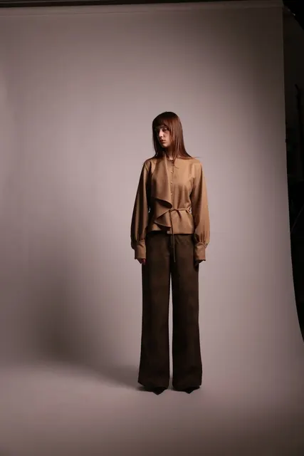 ベージュブラウス姿の女性が正面に立つスタジオポートレート