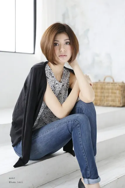 白い階段に座るショートヘアの女性、柔らかな表情
