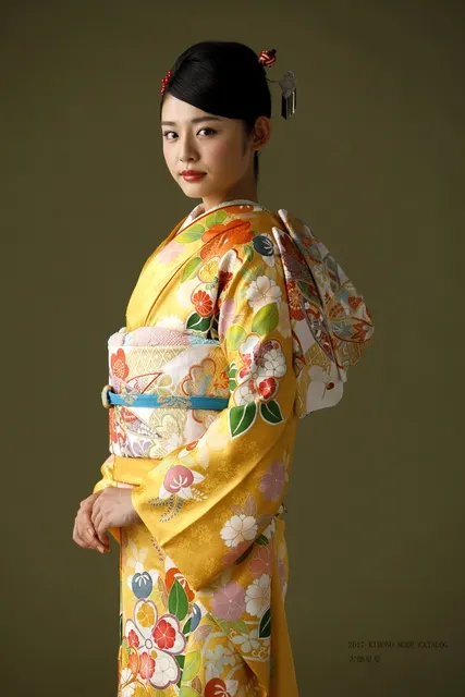 橙と白の振袖をまとった女性、横向きの上品な立ち姿
