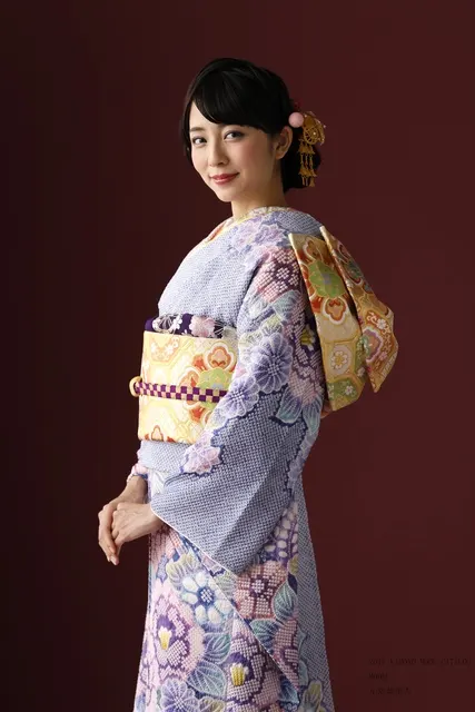 藤色の振袖に金の帯、柔らかな笑みを浮かべる女性
