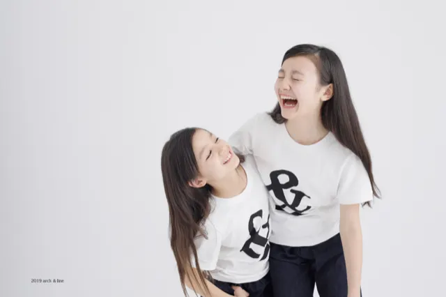 おそろいの白Tシャツで笑い合う姉妹、明るい表情