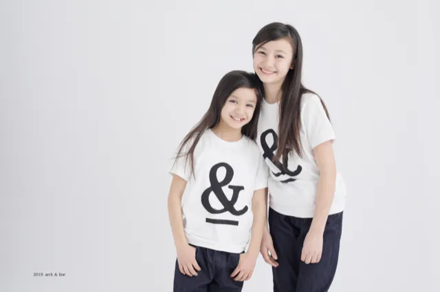 &ロゴのTシャツを着た姉妹が寄り添う笑顔の一枚