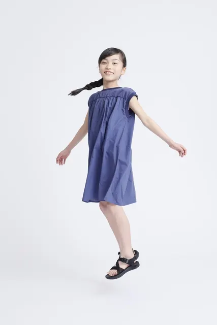 青いワンピースの女の子が宙に浮くように跳ねる瞬間