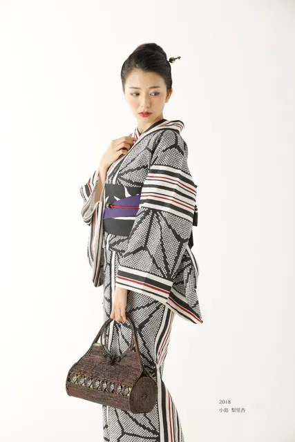 巾着バッグを提げ横向きに立つ浴衣姿の女性