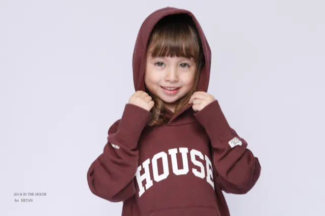 赤いHOUSEパーカーで両拳を上げてはにかむ女の子