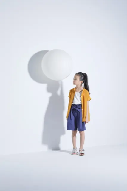 白い球体オブジェを見上げる黄色いカーディガンの女の子