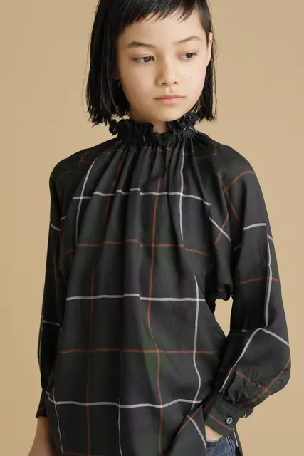 チェック柄ブラウスをまとい伏し目がちな女の子