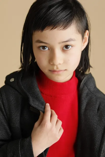 赤いニット姿で襟元にそっと手を添える女の子
