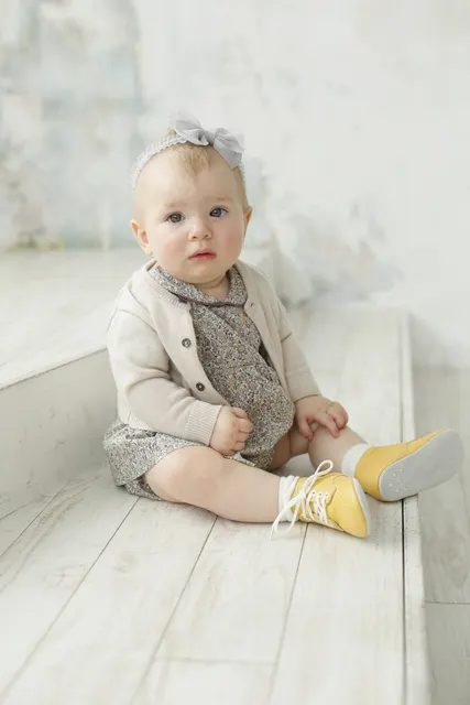 黄色い靴の赤ちゃんが床に座るナチュラルな一枚