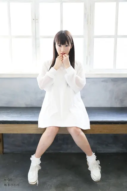 大きな窓辺のベンチに座る白いワンピースの女性