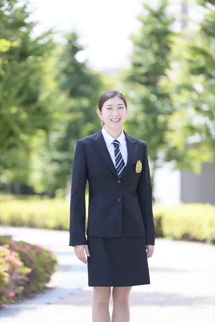 並木道でにこやかに立つスーツ姿の女性、修正版カット