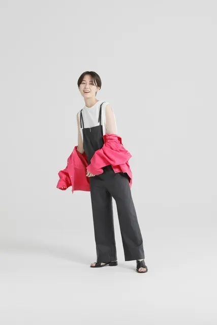 鮮やかなピンクのジャケットを羽織り微笑む女性