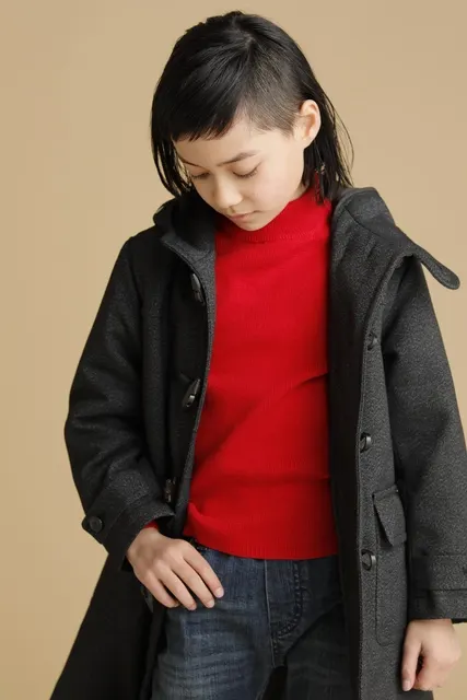 赤いニットにダッフルコートを羽織り下を向く男の子