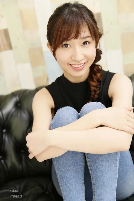 黒革ソファに座り微笑む女性、デニム姿のポートレート