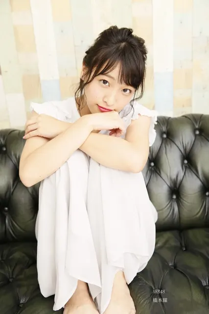 黒革ソファで膝を抱える白いワンピースの女性