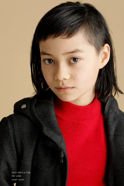 赤いニットで真っ直ぐこちらを見つめる女の子の横顔