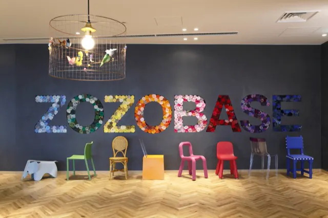 花で綴られたZOZOBASEの壁面とカラフルな椅子